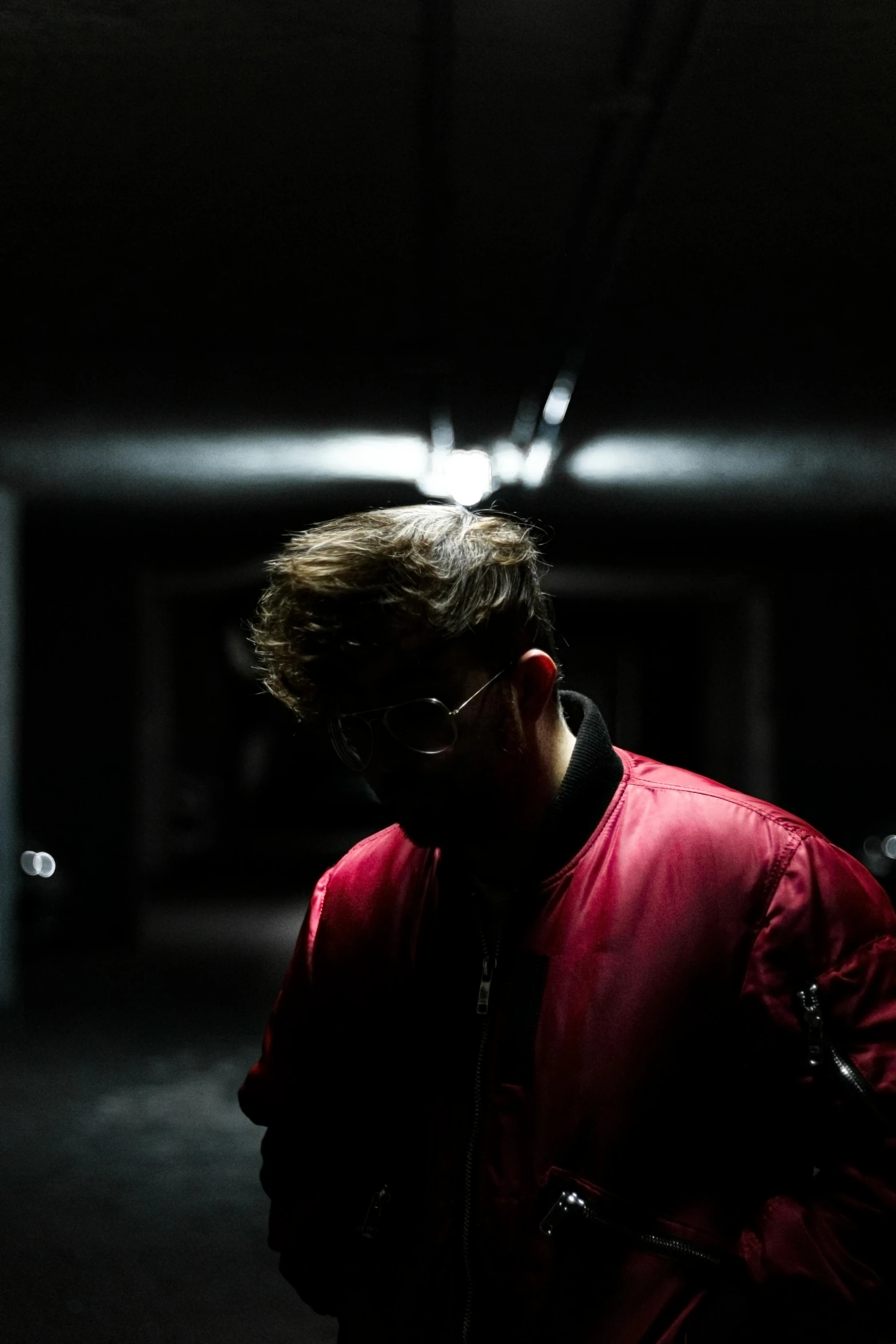 a man wearing red jacket standing in the dark