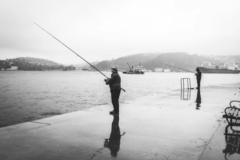 two men fishing in the water near benches