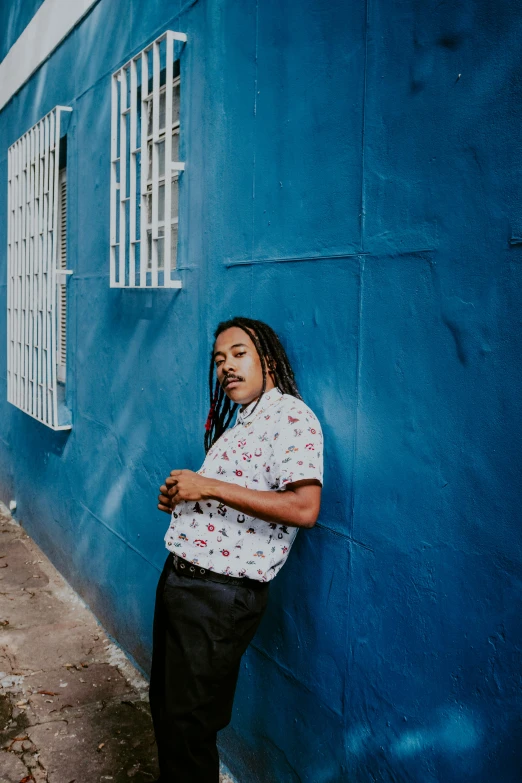 a man is leaning against the blue wall