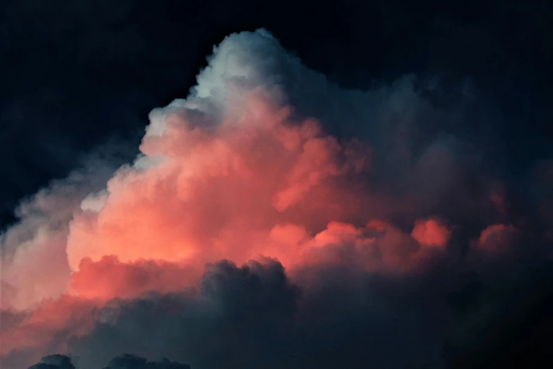 an airplane flying in the sky with a pink cloud