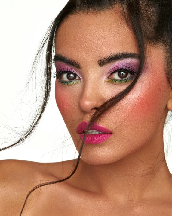 a woman wearing pink and purple make up