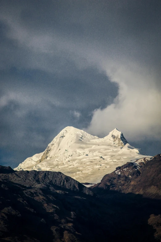 snow capped mountains sitting above a mountain covered in clouds