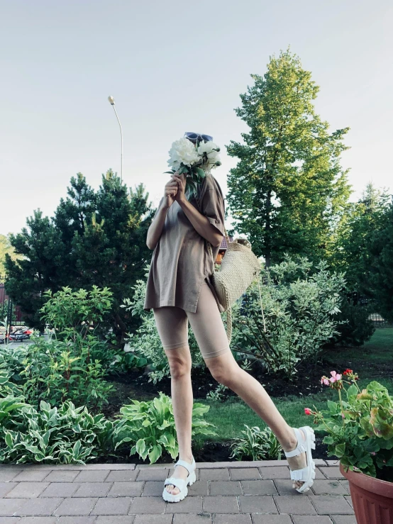 a woman standing in front of flowers on a brick walkway