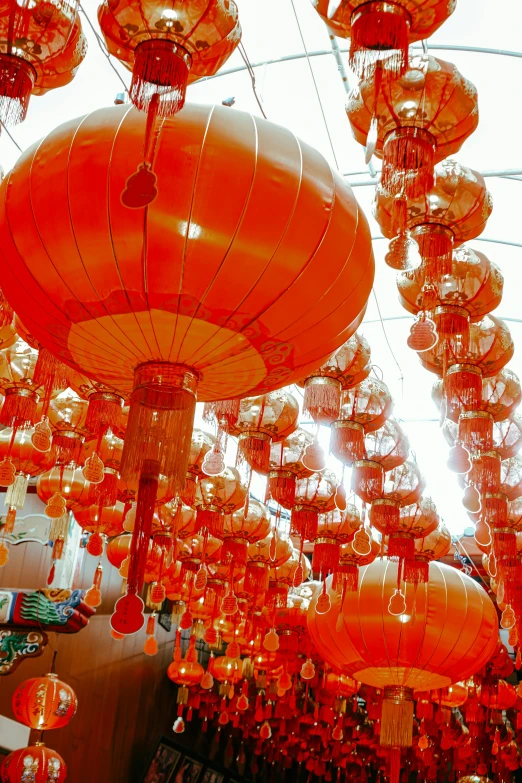 there is a large amount of red lanterns hanging from ceiling