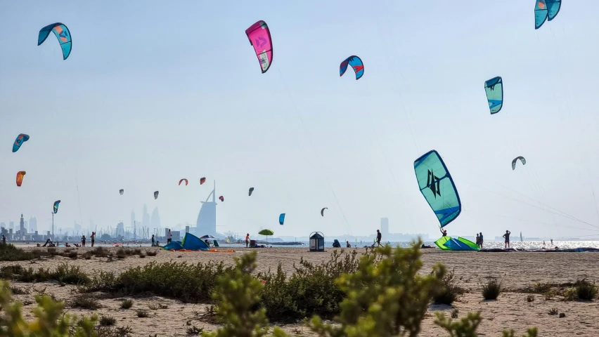 many kites fly in the sky and are being flown over the beach