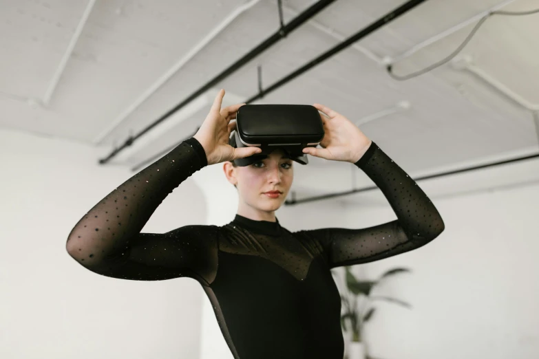 woman in a black leotard holding an object in her face