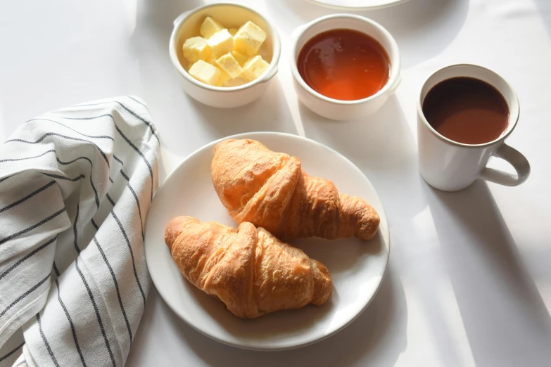 the breakfast plate includes croissants and two cups of tea