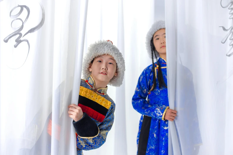 a  dressed in chinese clothing while a smaller boy watches