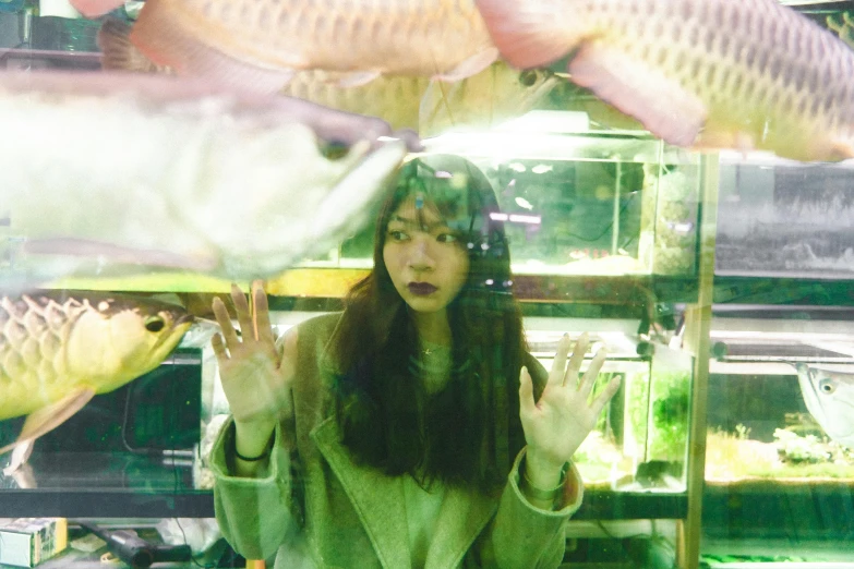 the woman is holding up her hands while she looks at some fish