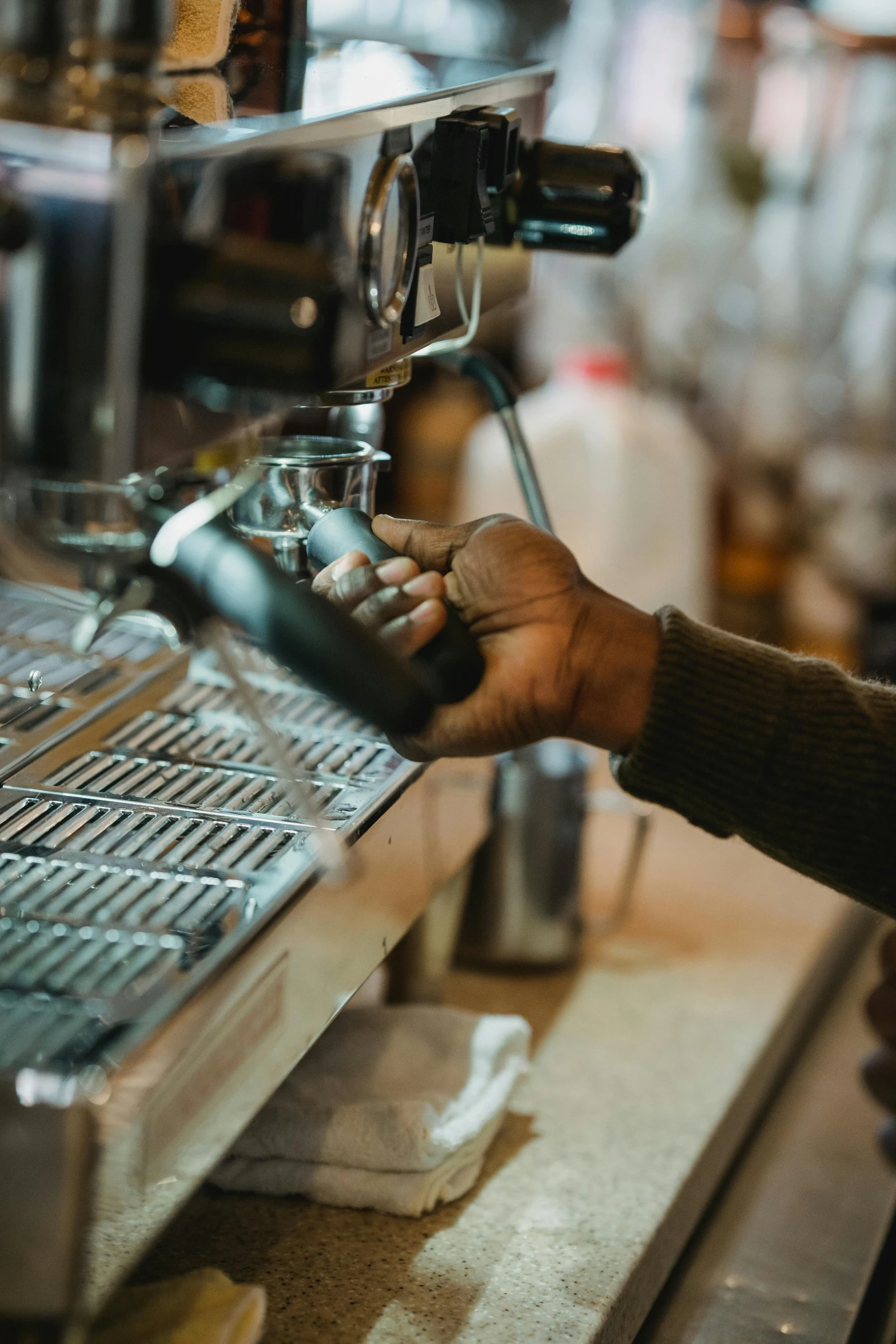 person pressing ons on a coffee machine at a shop