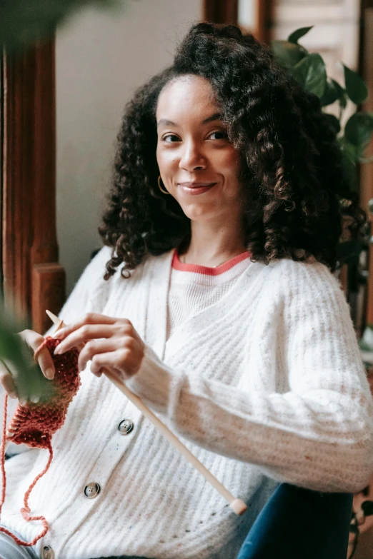 a young woman is knitting with her fingers