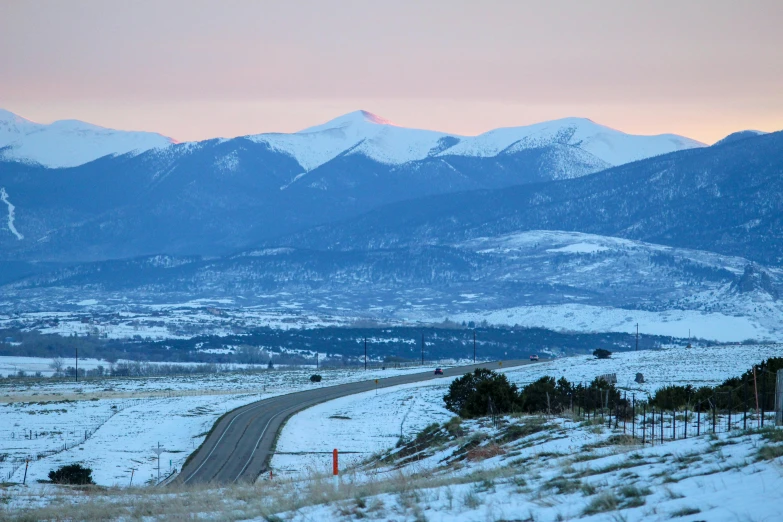 a snowy landscape shows the mountains, roads and buildings