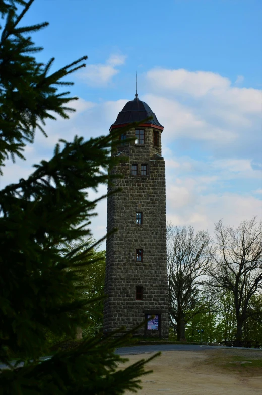 a large tower made out of bricks is sitting on a hill surrounded by trees