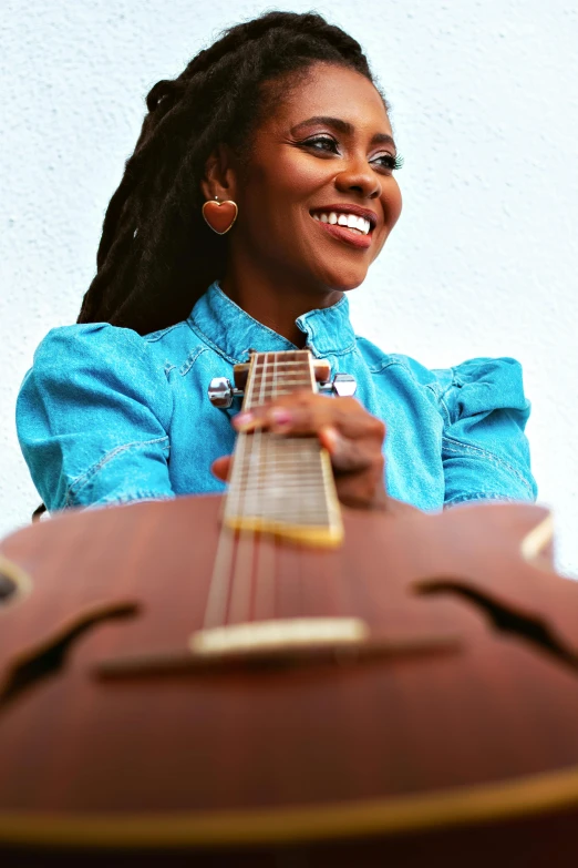 a woman smiles as she holds an acoustic guitar