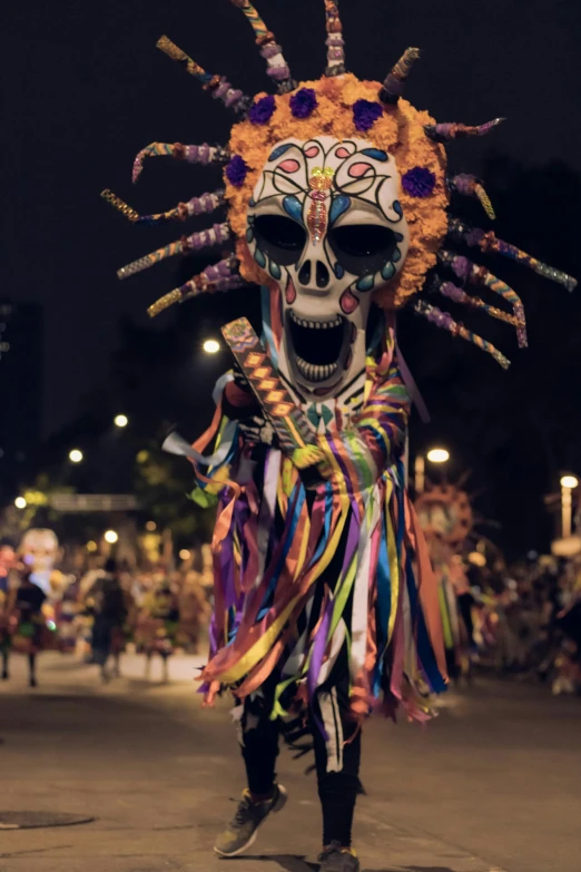 a man in a skeleton mask and headpiece walks down a street