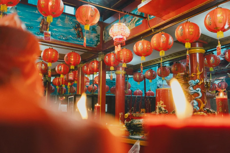 the people are standing under many red lanterns