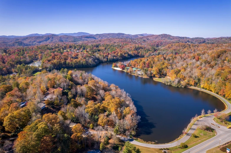 a road runs along the side of a lake with a lot of trees around