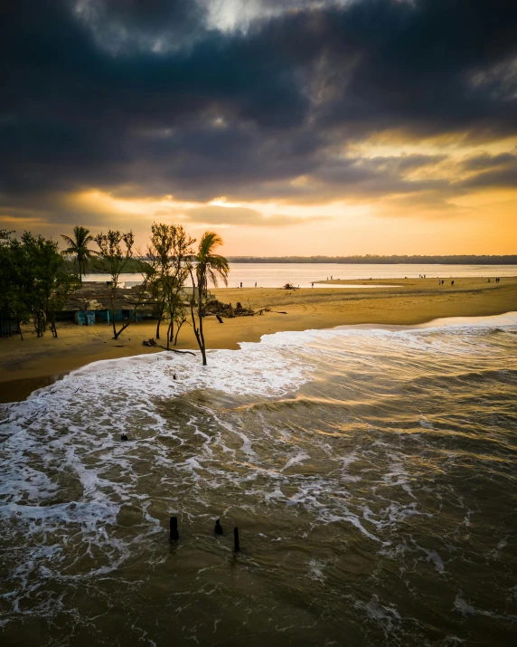 people standing in shallow water watching the sunset at the beach