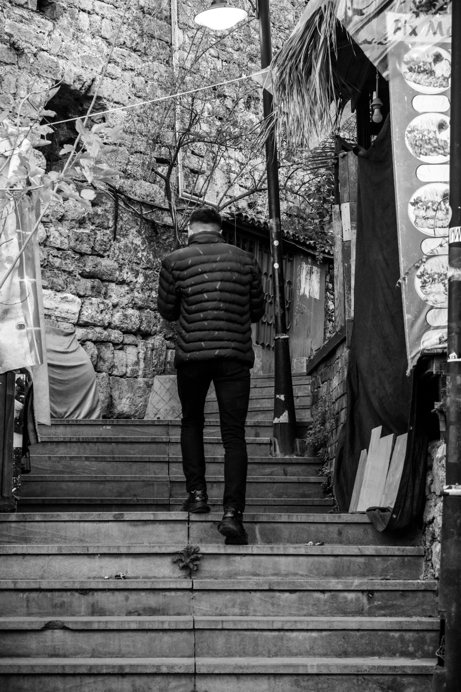 a man walks up stairs in front of a stone wall