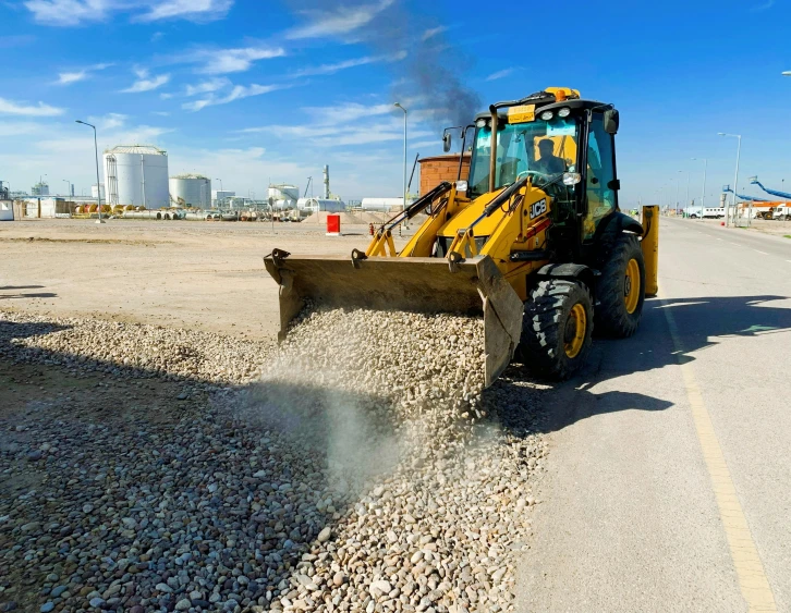 a tractor scooping dirt into the gravel