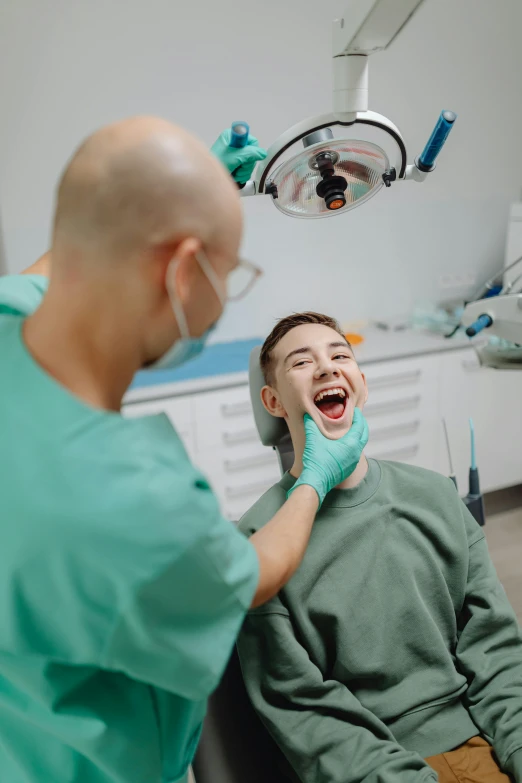 a man in green shirt sitting next to a dentist
