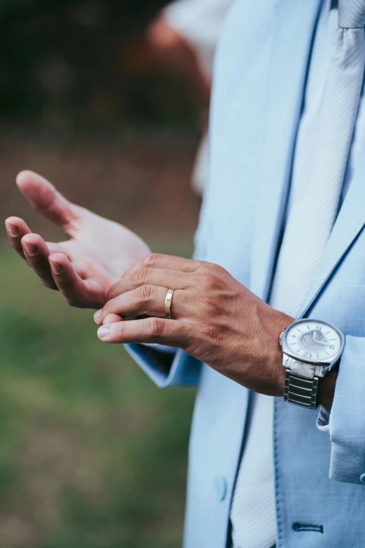 a person in blue suit and gold ring holding out their hands