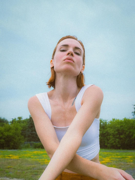 a beautiful woman with red hair and white shirt sitting down with her arm resting on the bench