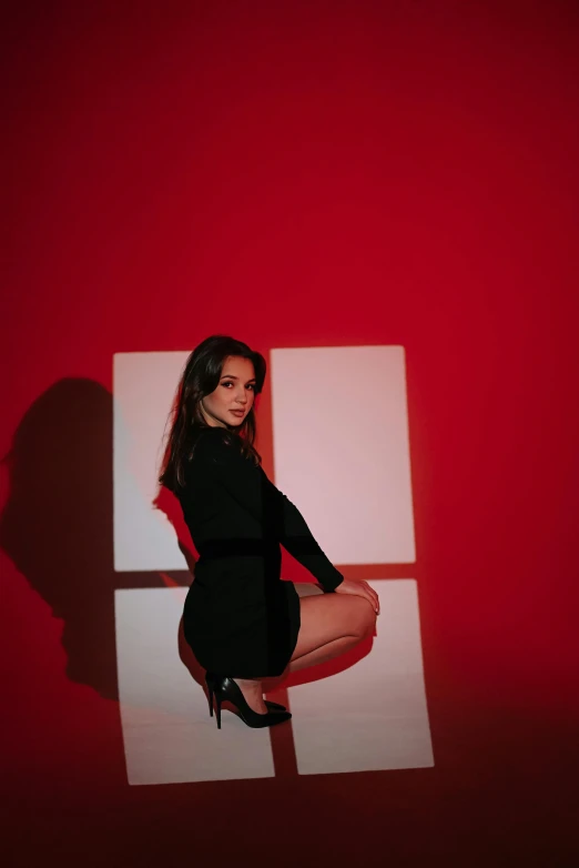 a beautiful woman sitting on the ground near a wall