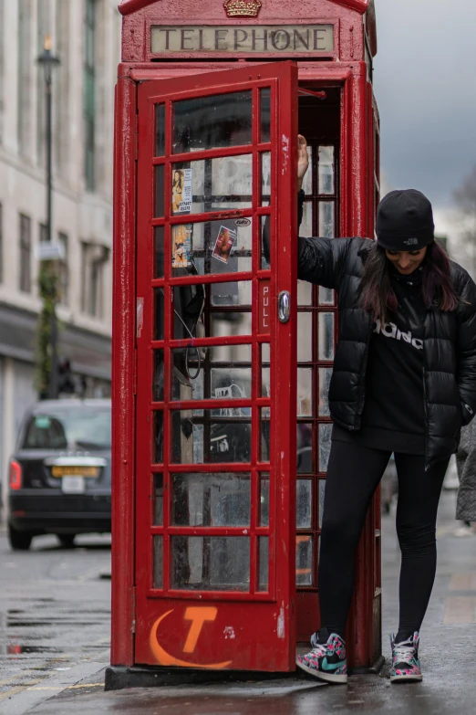 a woman leaning out of a phone booth in the middle of the street