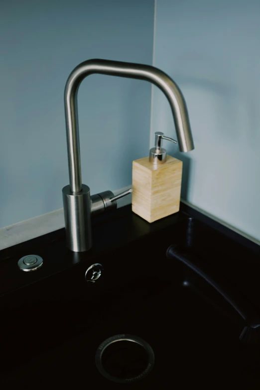 the black sink is next to a faucet and soap dispenser