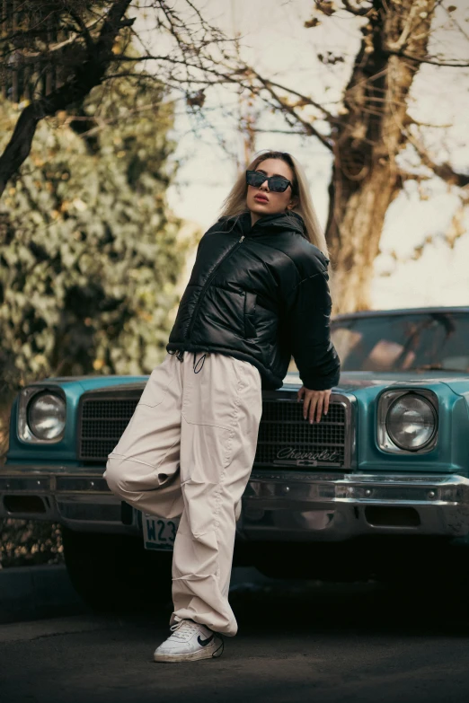 a woman wearing shades poses near her car