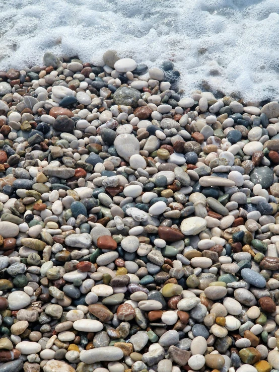 a bunch of rocks laying on top of a beach next to the water