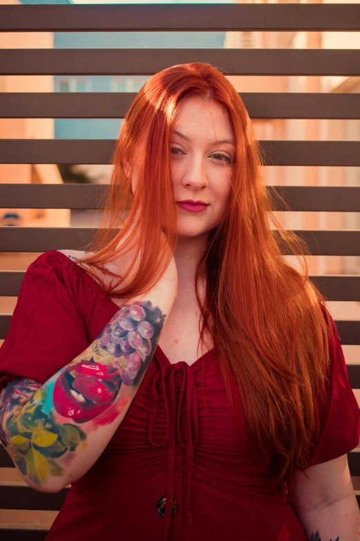 red haired woman with arm tattoo looking at camera
