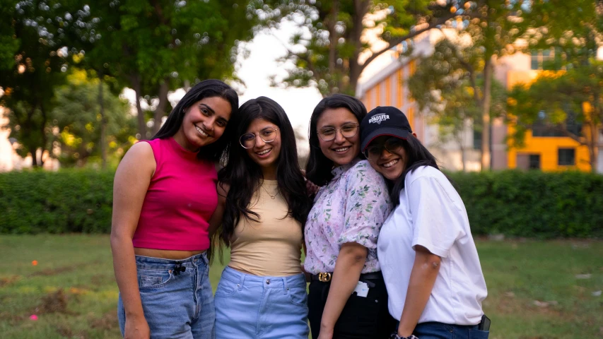 four girls posing together in a park on the sidewalk