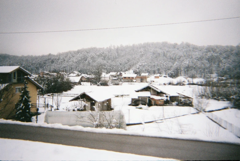 an aerial view of snow covered town with hills in background