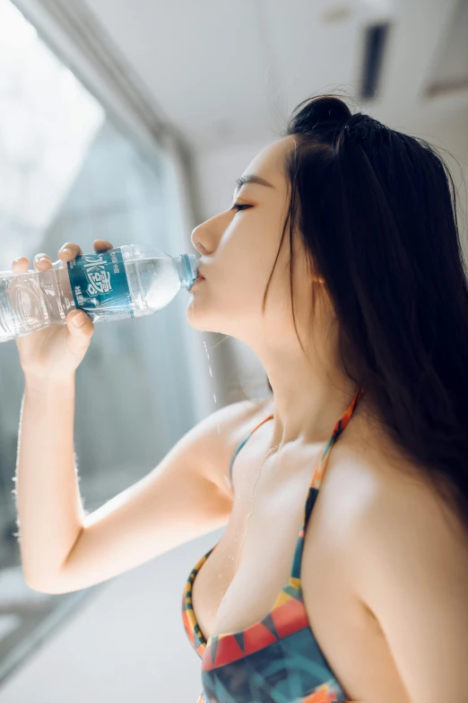 young woman with long black hair taking a drink of water