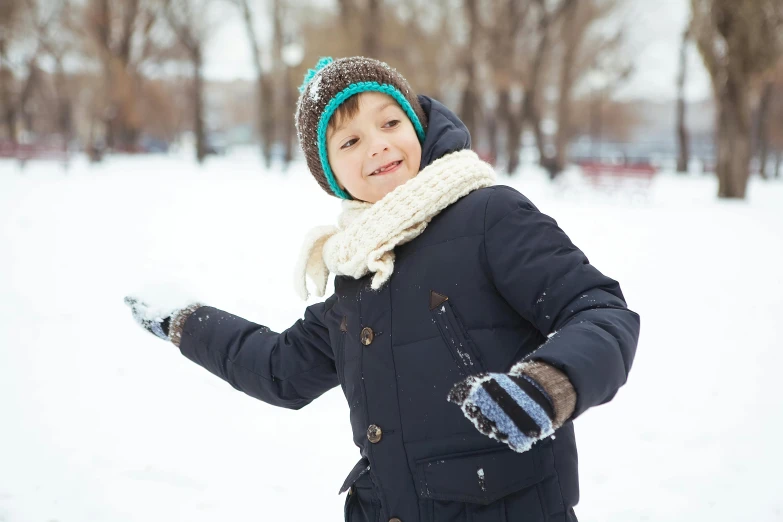 little boy outside in the snow, wearing gloves and wearing warm clothes