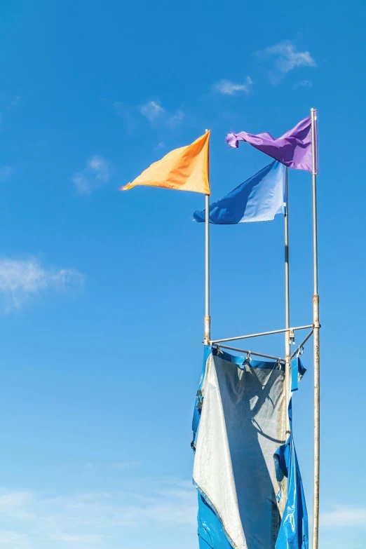 several colorful flags hanging in the air under a blue sky