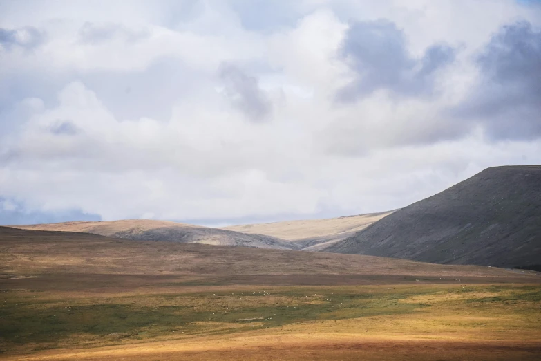 a very large grassy plain with some clouds above it