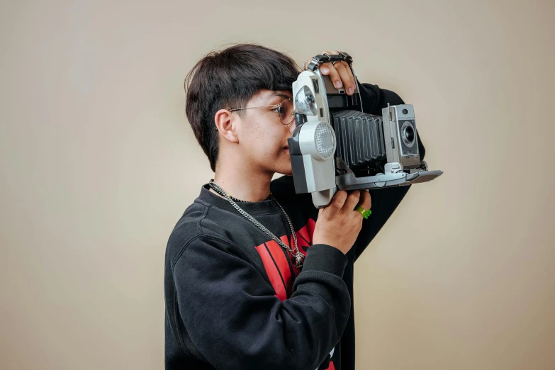 a young man holding an old camera to his face