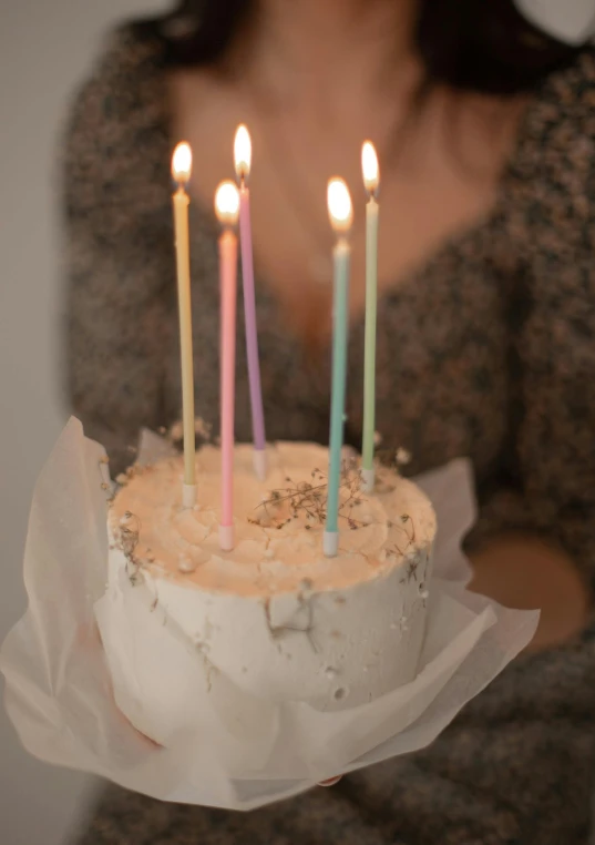 a woman holding up a cake that has been decorated with candles
