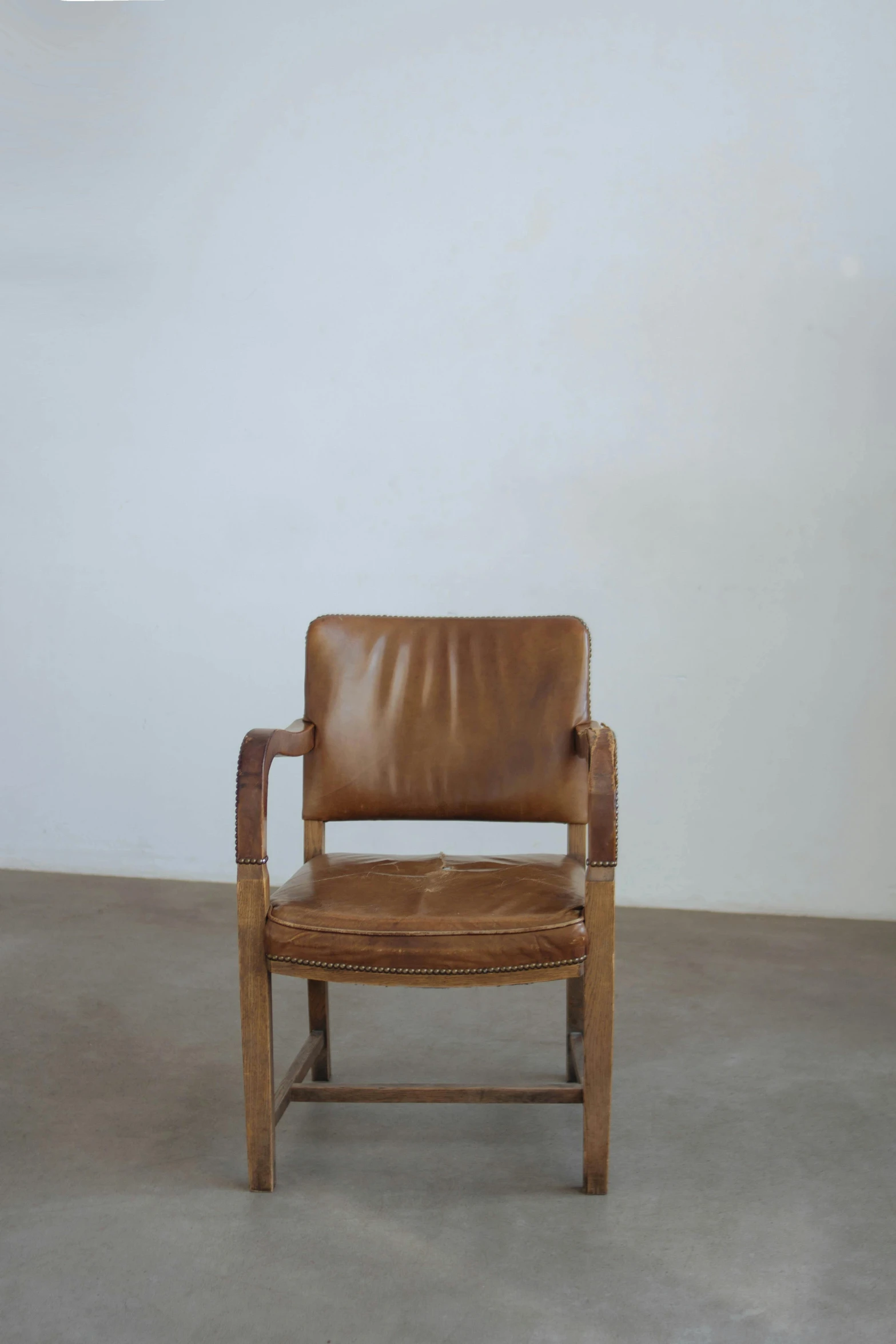 a brown leather chair against a plain white wall