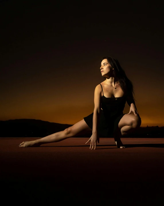 a woman crouches down in the middle of a dark background
