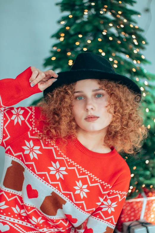 a person with a christmas sweater and hat posing for a picture