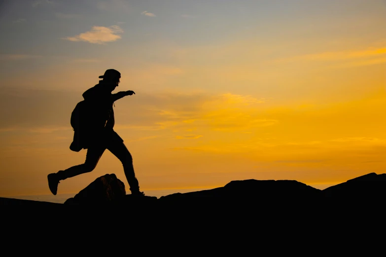 a person running in the sunset behind rocks