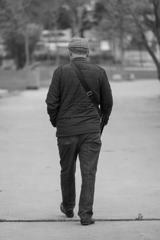 an older man walking on the sidewalk while wearing a jacket