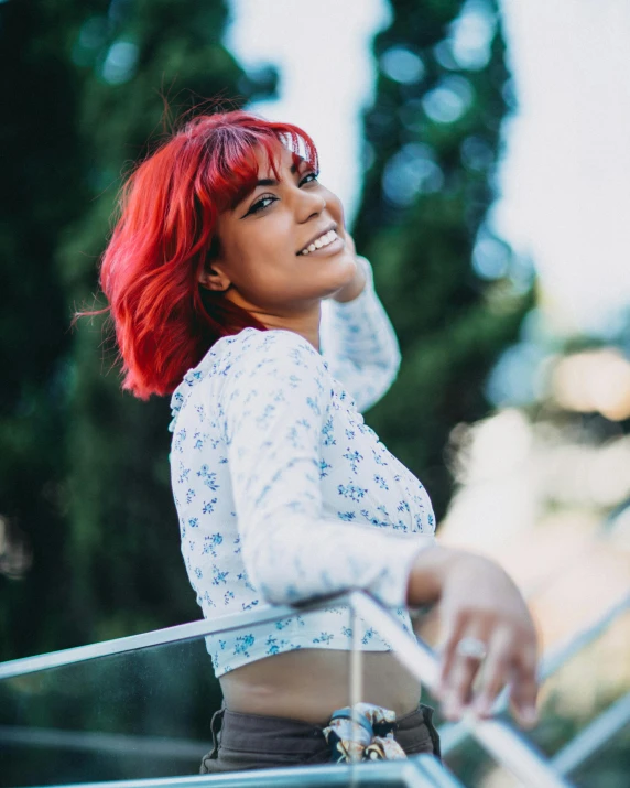 a young woman with red hair in a white top standing next to stairs