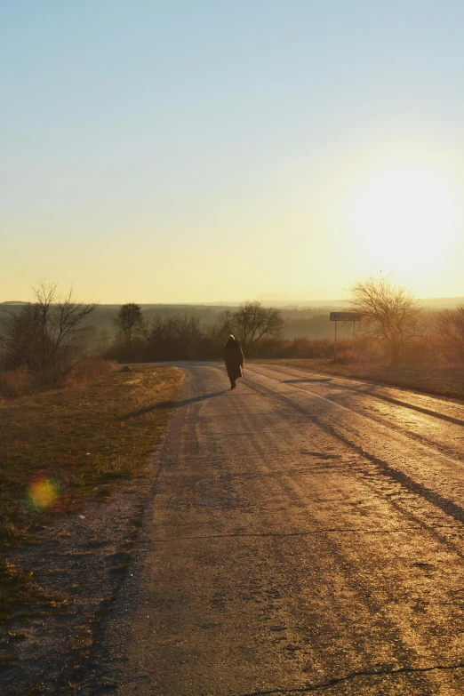 the man is walking down the road in the sun