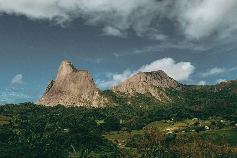 the green hills are in front of the mountain tops