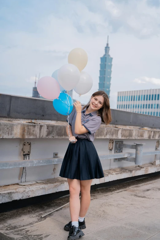 a woman holding some balloons up near a building